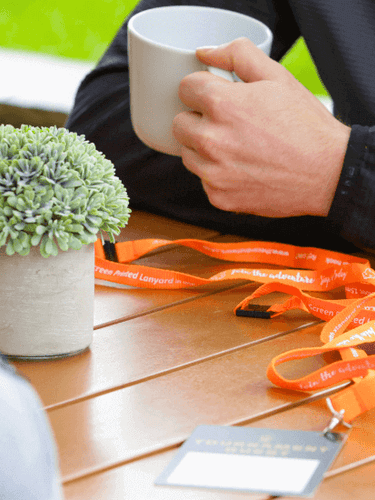 Large Printed Event Passes on a table with an orange lanyard attached